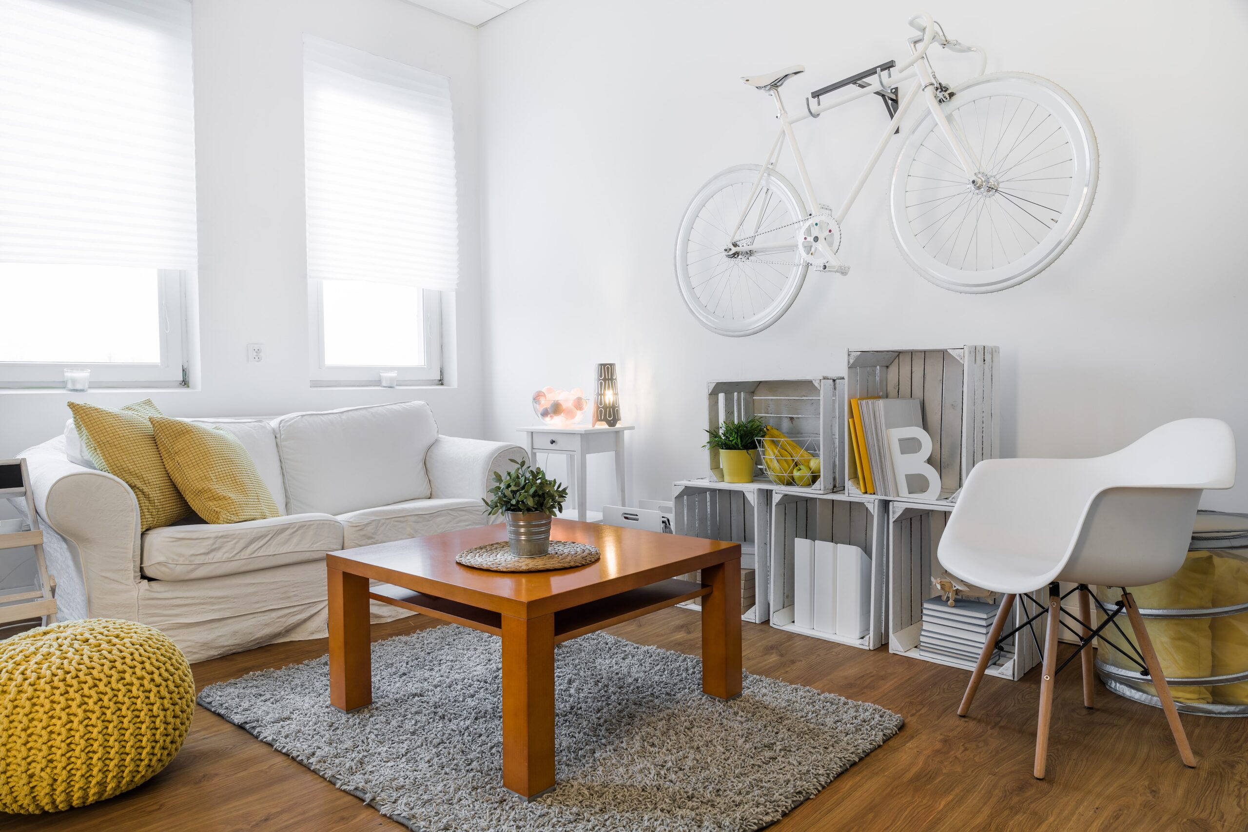 living room with a white couch, wooden table and a white bicycle on the wall.